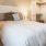One Bedroom Apartments in Sparks NV - Waterfront at the Marina - Carpeted Bedroom with a Large Bed, Twin Nightstands, Lamps, White Walls, and a Spacious Closet