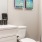 Bath with single vanity and large mirror with plenty of light.